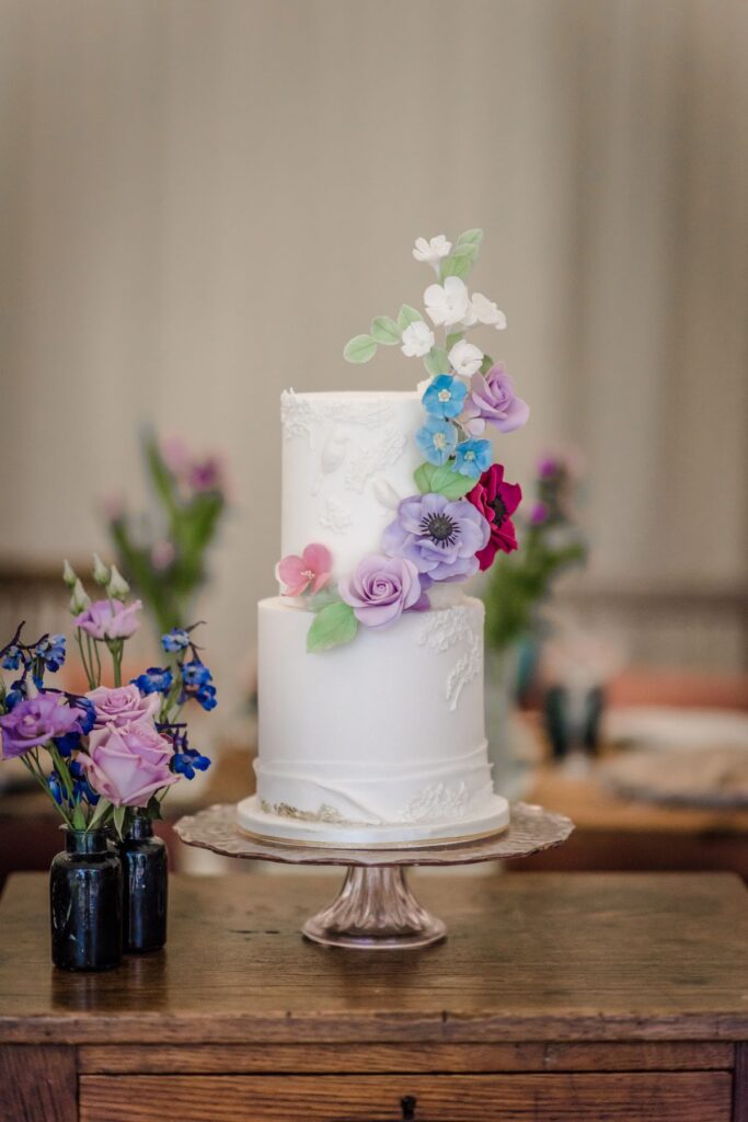 A white wedding cake with edible pretty flowers created for an elopement at the Castle Westenhanger kent england