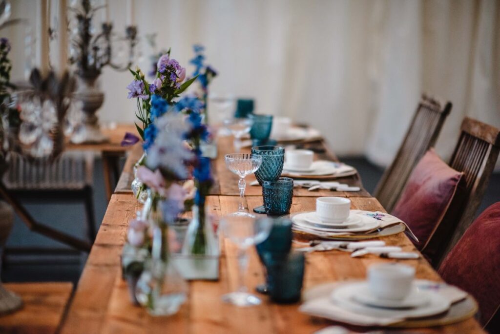 Blue glasses on wooden tables make up a beautiful tablescape for a petitie wedding at the Castle Westenhanger