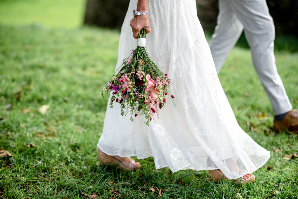 An eloped couple walk on grass