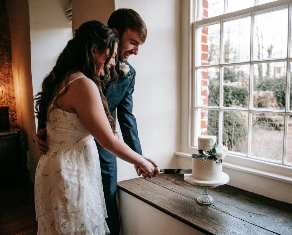 The eloped couple cut the elopement vegan wedding cake in the window sill of the Castle Westenhanger, Kent, Southeast England