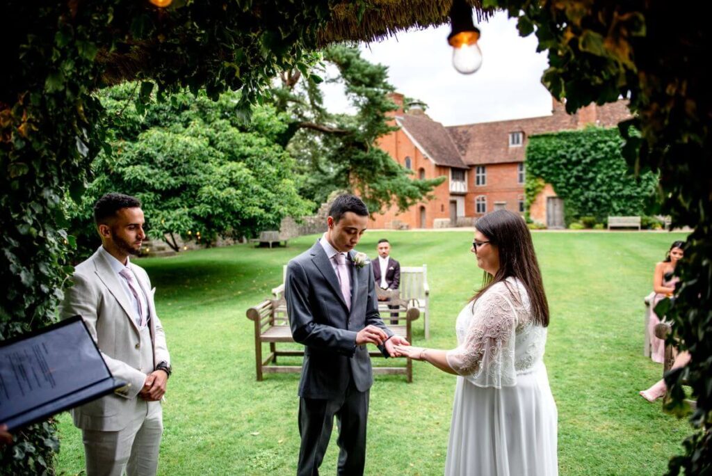 The eloping couple exchange rings in front of their tiny gathering of friends and family at the castle westenhanger, kent, England