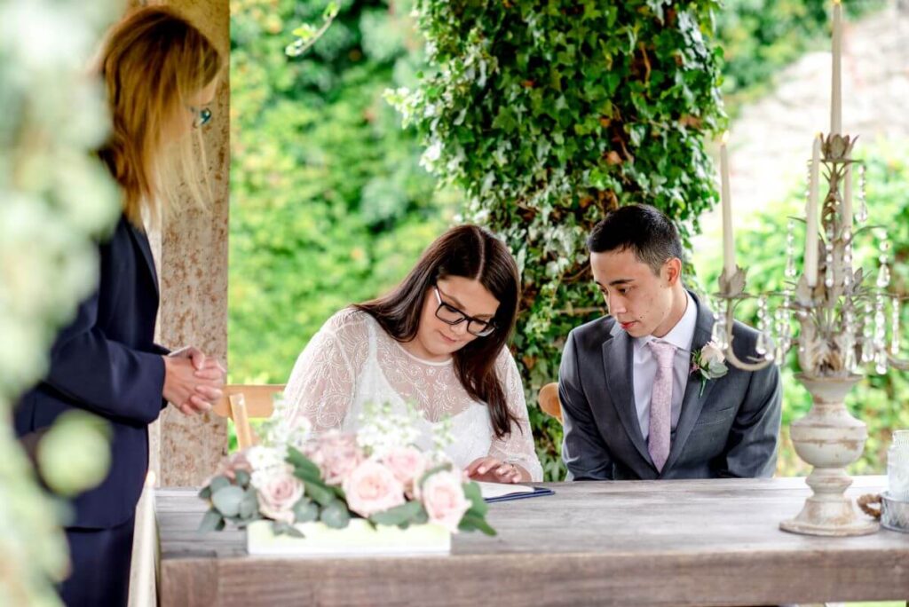 The eloping couple sign the register in front of their tiny gathering of friends and family at the castle westenhanger, kent, England
