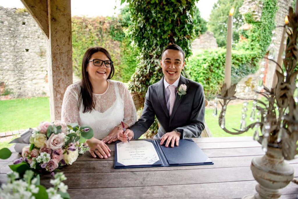 The eloping couple sign the register in front of their tiny gathering of friends and family at the castle westenhanger, kent, England