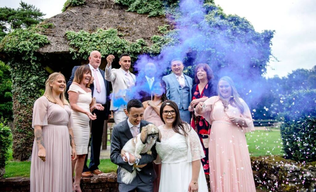 The elopement party enjoy smoke bombs infront of the thatched gazebo at the Castle Westenhanger, Kent, Southeast England