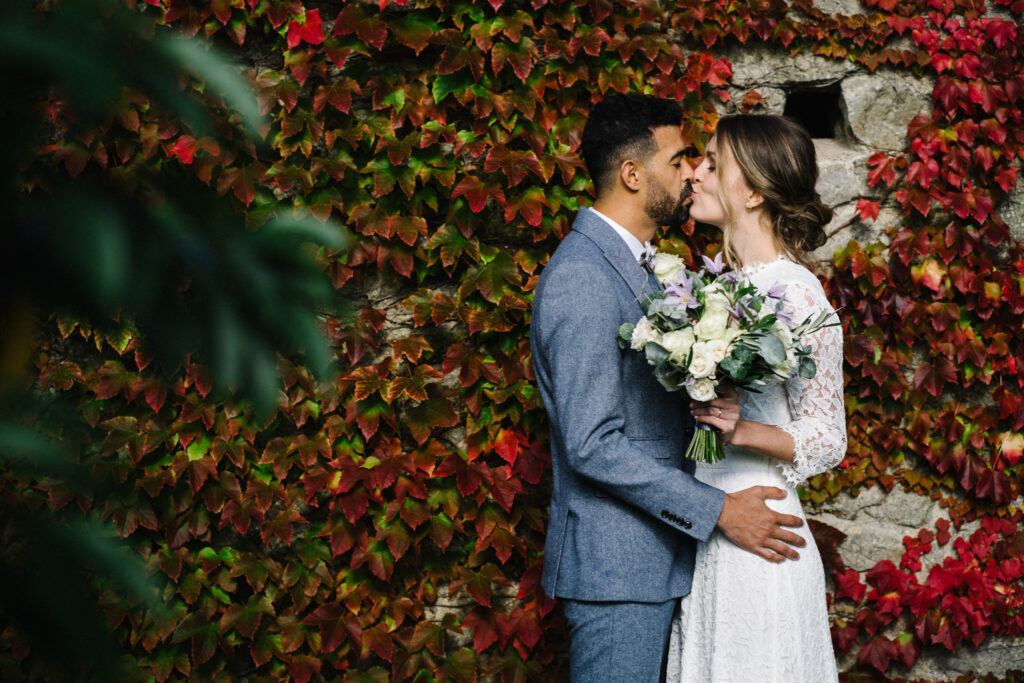 The couple enjoy moments with their elopement photographer in front of the Virginia creeper, (Parthenocissus quinquefolia) outside the Castle Westenhanger in Kent, England