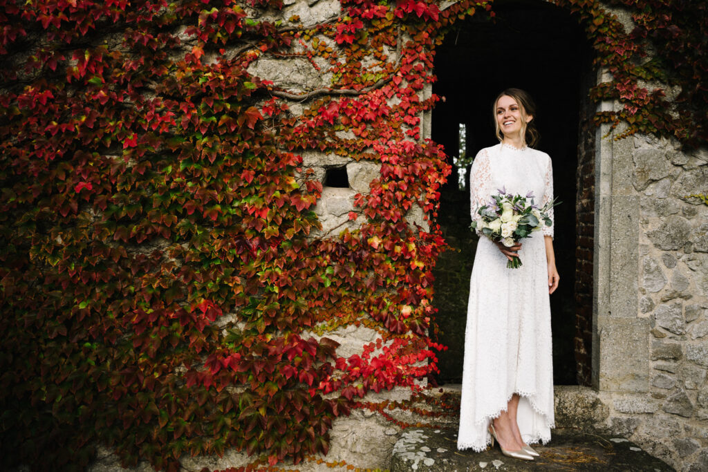 The couple enjoy moments with their elopement photographer in front of the Virginia creeper, (Parthenocissus quinquefolia) outside the Castle Westenhanger in Kent, England