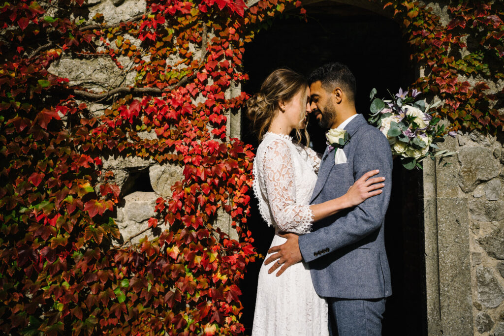 The couple enjoy moments with their elopement photographer in front of the Virginia creeper, (Parthenocissus quinquefolia) outside the Castle Westenhanger in Kent, England