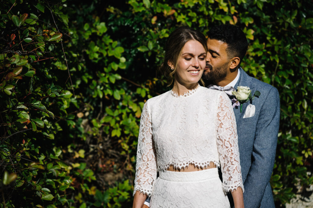The couple enjoy moments with their elopement photographer in front of the Virginia creeper, (Parthenocissus quinquefolia) outside the Castle Westenhanger in Kent, England