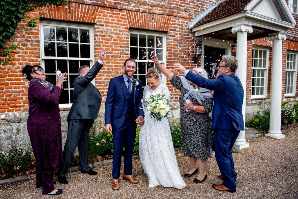 The intimate gathering throw confetti over the just married couple outside the fortified 14th Century manor house in Kent
