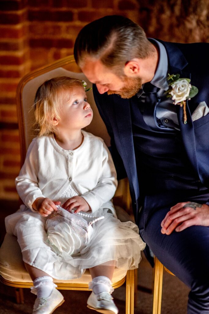 A groom dressed in a blue suit with his baby girl just before saying I do at the Castle Westenhanger in Kent