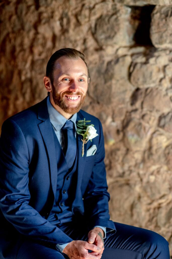 A groom dressed in a blue suit with his elopement buttonhole before saying I do at the Castle Westenhanger in Kent