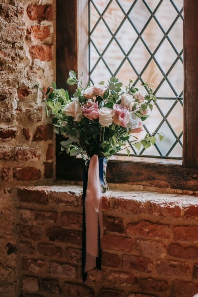 A bouquet of blush and pink roses,tied with a blue silk and vintage pink silk ribbon sat on one of the Castle Westenhanger windowsills