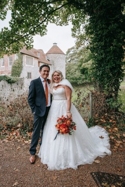 A couple stand with the Dovecote at the Castle Westenhanger in the background licenced for tiny, small, micro, petite weddings and elopements