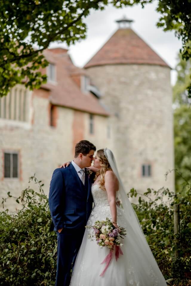 A couple stand with the Dovecote at the Castle Westenhanger in the background licenced for tiny, small, micro, petite weddings and elopements