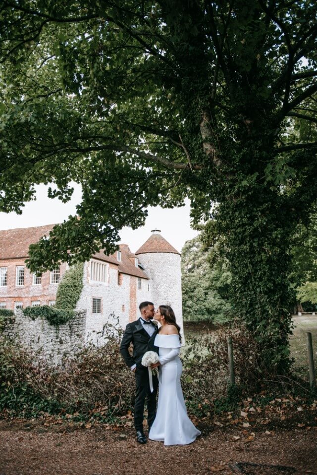 A couple stand with the Dovecote at the Castle Westenhanger in the background licenced for tiny, small, micro, petite weddings and elopements
