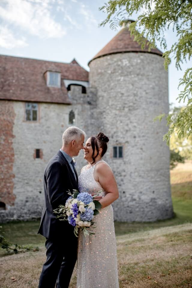 A couple stand with the Dovecote at the Castle Westenhanger in the background licenced for tiny, small, micro, petite weddings and elopements