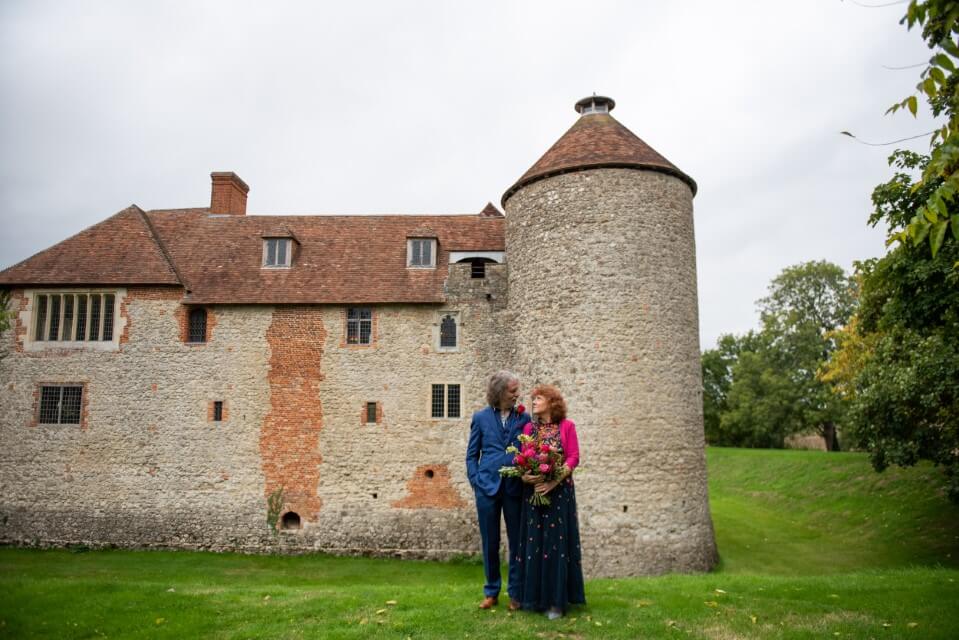 A couple stand with the Dovecote at the Castle Westenhanger in the background licenced for tiny, small, micro, petite weddings and elopements