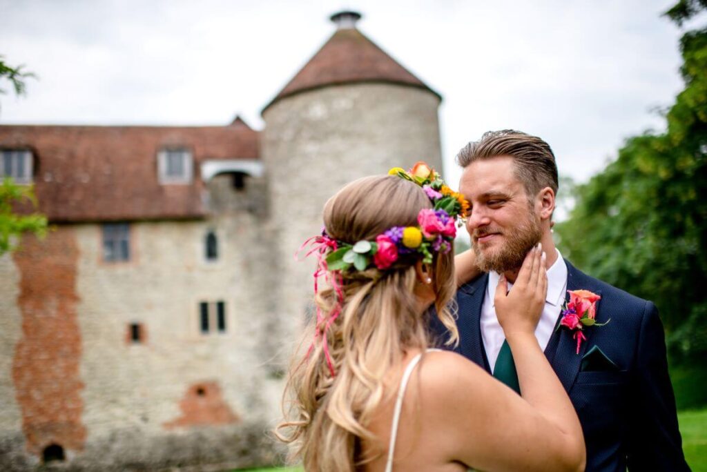 A couple stand with the Dovecote at the Castle Westenhanger in the background licenced for tiny, small, micro, petite weddings and elopements