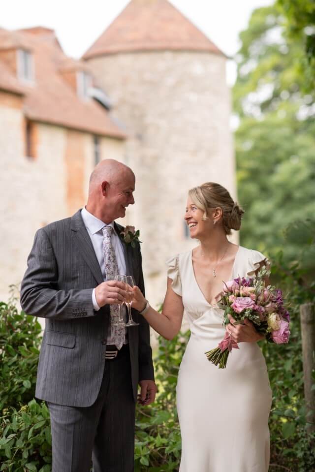 A couple stand with the Dovecote at the Castle Westenhanger in the background licenced for tiny, small, micro, petite weddings and elopements