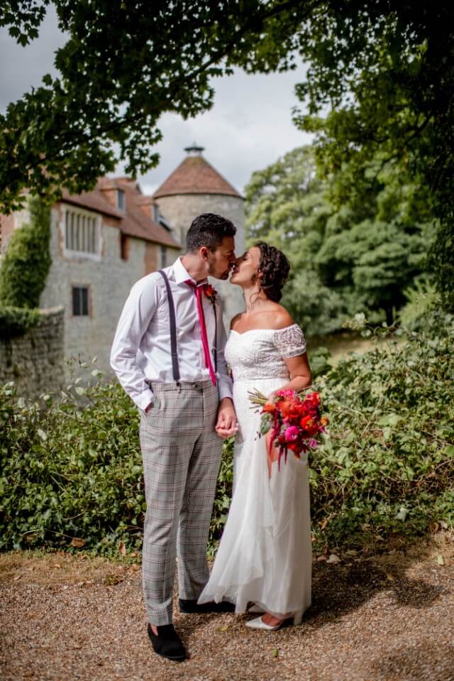 A couple stand with the Dovecote at the Castle Westenhanger in the background licenced for tiny, small, micro, petite weddings and elopements