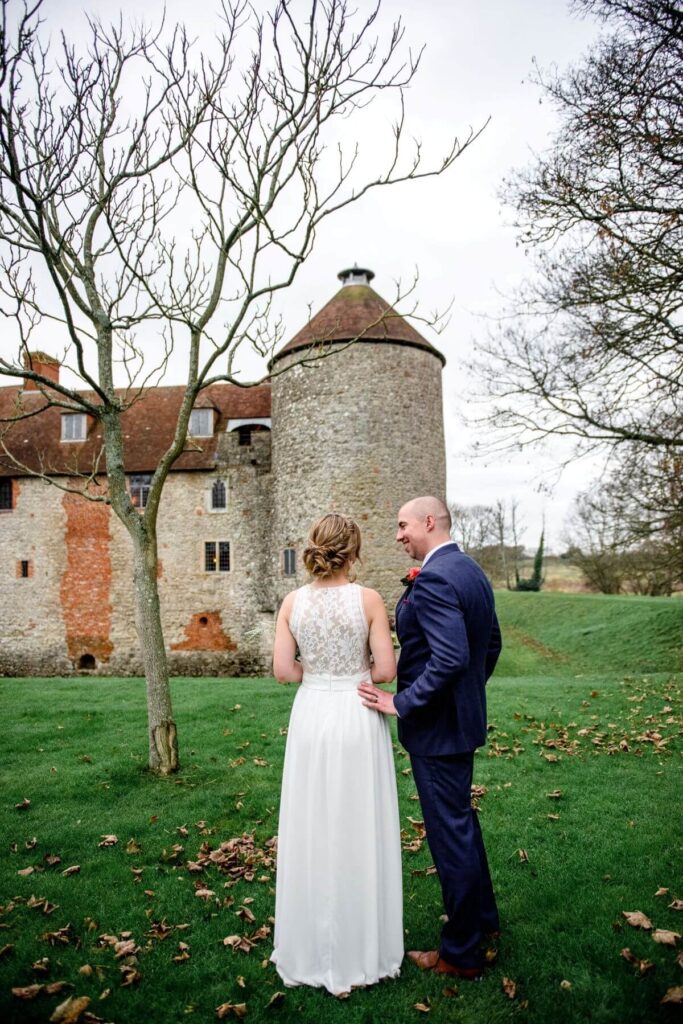 A couple stand with the Dovecote at the Castle Westenhanger in the background licenced for tiny, small, micro, petite weddings and elopements