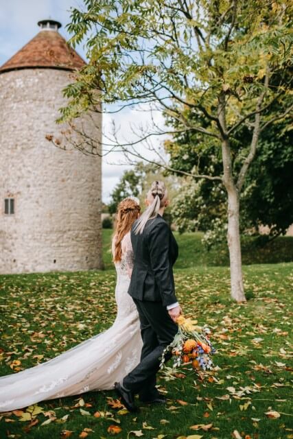 A couple stand with the Dovecote at the Castle Westenhanger in the background licenced for tiny, small, micro, petite weddings and elopements
